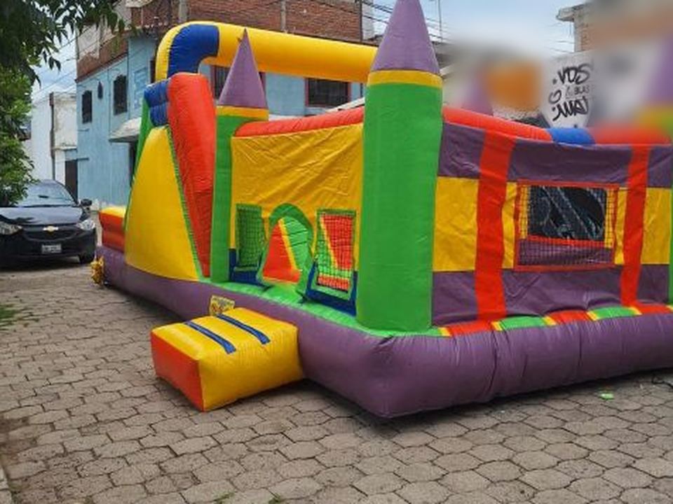 Castillo inflable con torres moradas y rampa amarilla