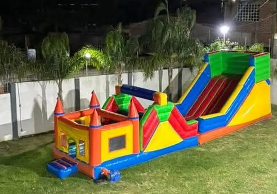 Castillo aventura de Diversiones Papus instalado en un jardín al anochecer